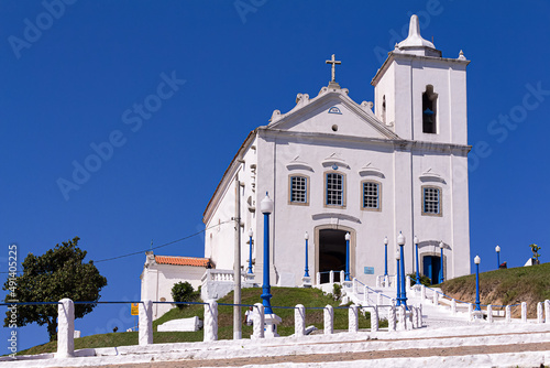 Ponto turístico da praia saquarema a igreja histórica no estilo barroco, toda branca com detalhes azuis e com a grande escadaria na frente num lindo dia de sol.  photo