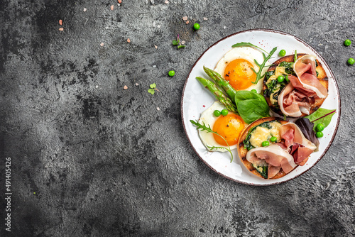 Delicious breakfast or snack. Grilled Toast witch Asparagus, fried egg, bacon jamon, ham, prosciutto on dark background. Healthy fats, clean eating for weight loss. Long banner format. top view