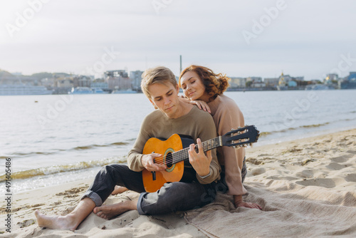 Happy couple in love. Stunning sensual portrait of a young couple. Young man playing guitar for his beloved girl. © Igor