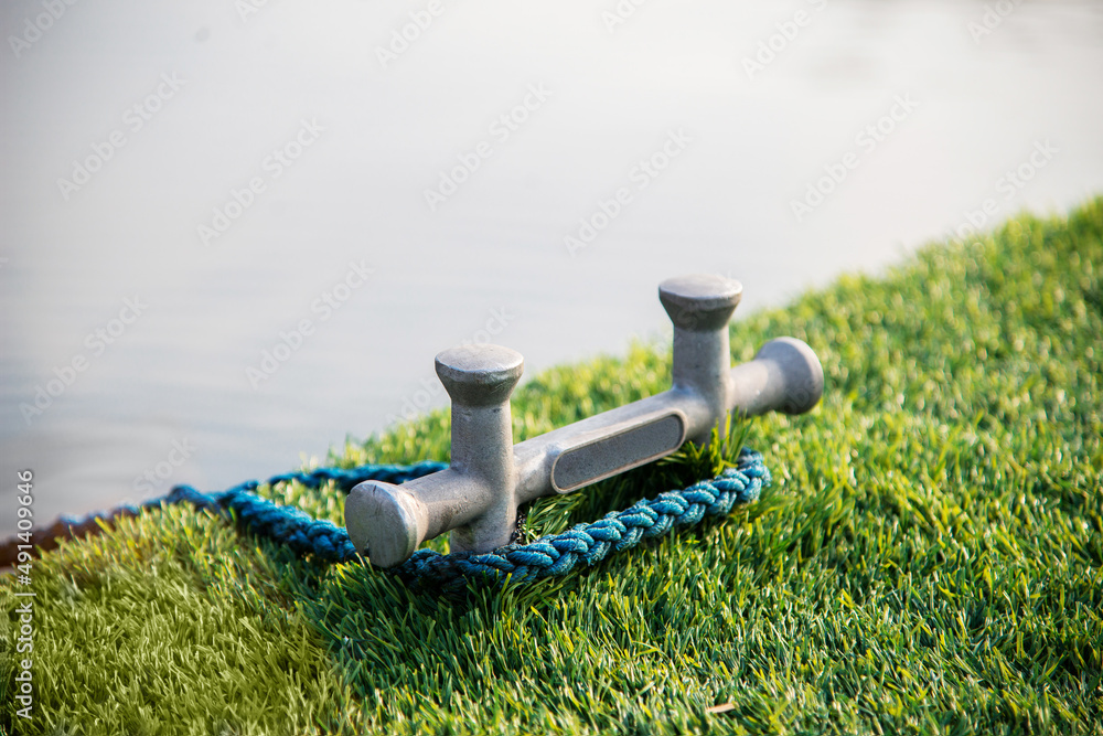 Fototapeta premium Double cross bollard or bitteng with a tied rope on the dock. towing mooring gear