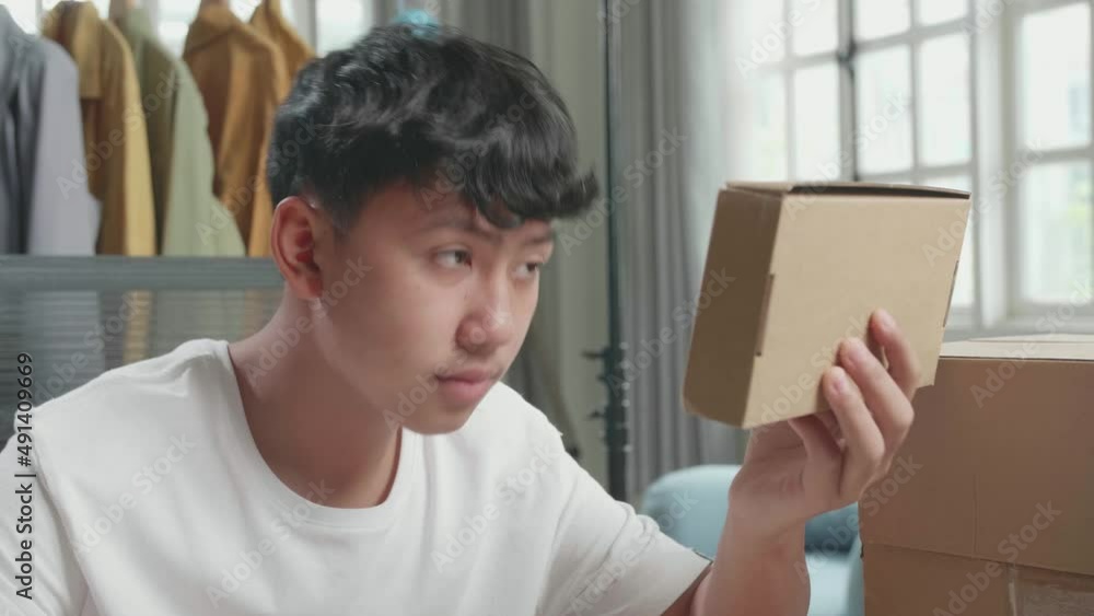 Close Up Of Asian Man Online Seller Look At The Package And Write In The Notebook While Selling Clothes At Home
Close Up Of Asian Man Online Seller Look At The Package And Write In The Notebook While Selling Clothes At Home