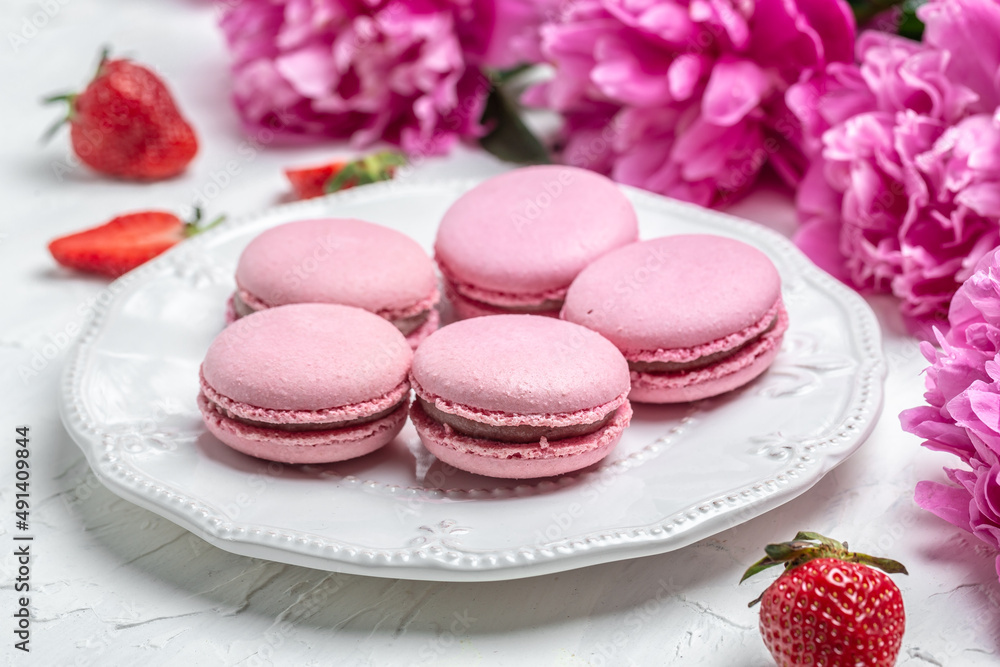 pink macaron or macaroon cakes with peony rose on a white background. Banner, flyer, beautiful postcard, top view pink macaron or macaroon cakes with peony rose on a white background. Banner, flyer, beautiful postcard, top view