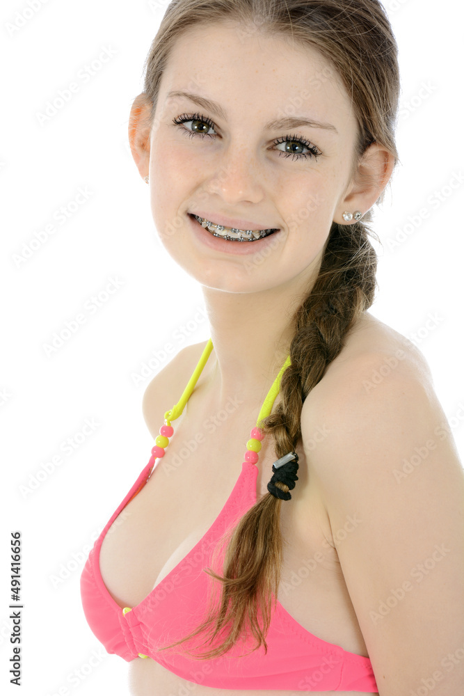 Portrait of a cute teen girl posing in pink bikini in studio isolated on white
