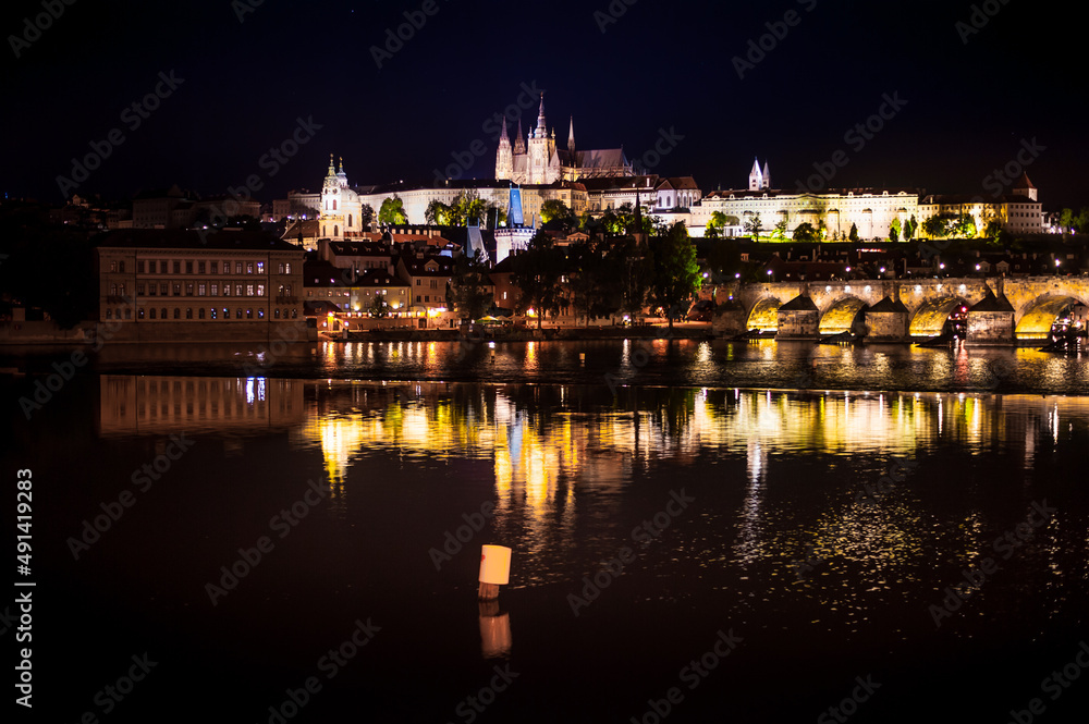 perspective to a castle of the night prague at dusk from the side of the Vltava River