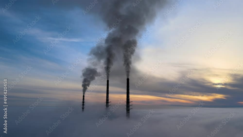 Aerial view of coal power plant high pipes with black smoke moving up polluting atmosphere at sunset Aerial view of coal power plant high pipes with black smoke moving up polluting atmosphere at sunset