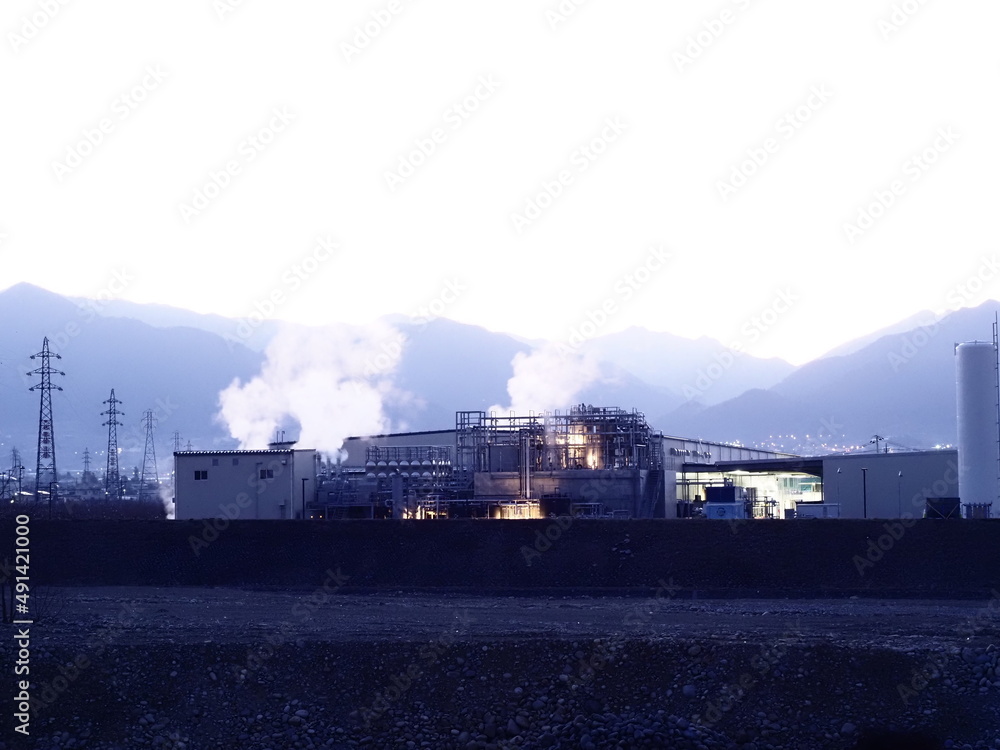 朝焼けの中、煙を出す工場