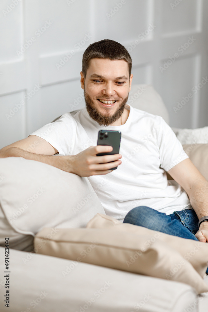 young man at home on the couch talking video call from the phone. young man at home on the couch talking video call from the phone.