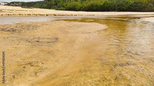 Pequeno rio que se encontra com o mar na praia dos espelhos que é um apelido devido ao efeito causado pelo reflexo do sol nas piscinas naturais quando avistadas do mar no povoado de Caraíva, Bahia. photo