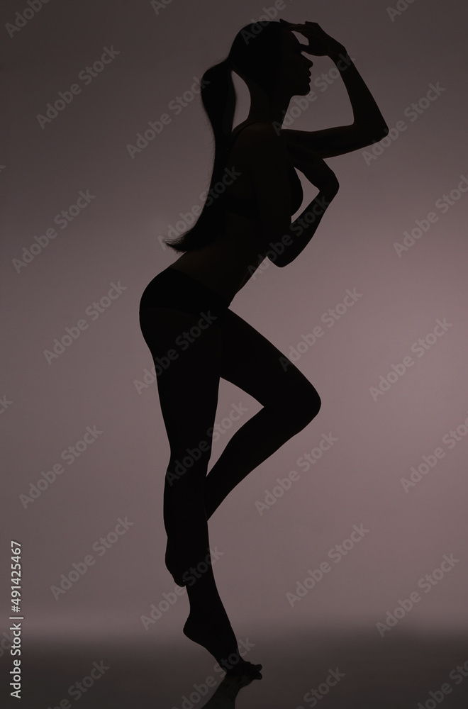 Silhouetted beauty. Studio silhouette of a beautiful woman in lingerie against a gray background.