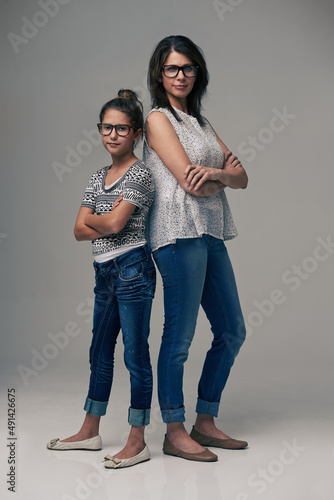 Like mother like daughter. Studio shot of a trendy mother and daughter against a gray background.