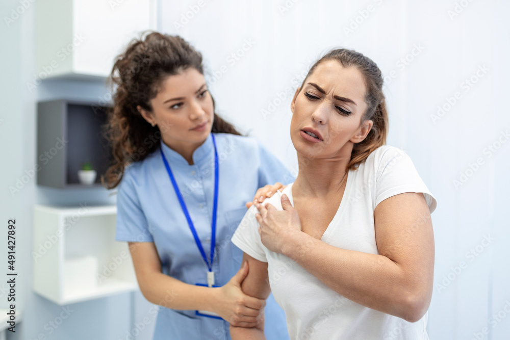 Woman doctor osteopath in medical uniform fixing woman patients shoulder and back joints in manual therapy clinic during visit. Professional osteopath during work with patient concept Woman doctor osteopath in medical uniform fixing woman patients shoulder and back joints in manual therapy clinic during visit. Professional osteopath during work with patient concept