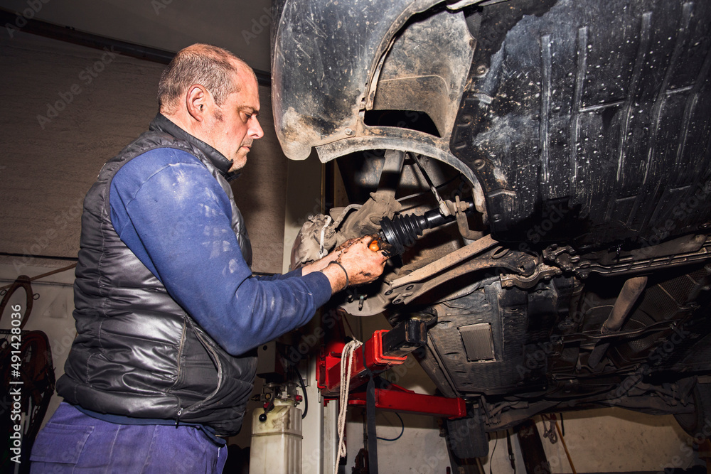 mechanic in workshop changing a drive shaft car mechanic in workshop changing a drive shaft car