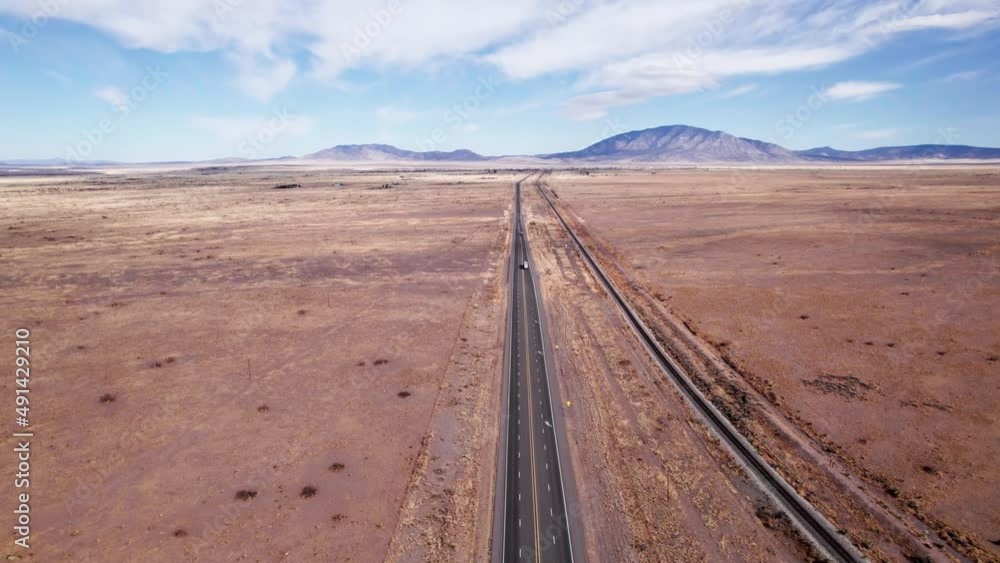 Drone shot over a desert highway with a semi truck and car driving