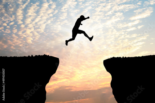 Foto Silhouette young man jumping over precipice between two rocky mountains at sunset