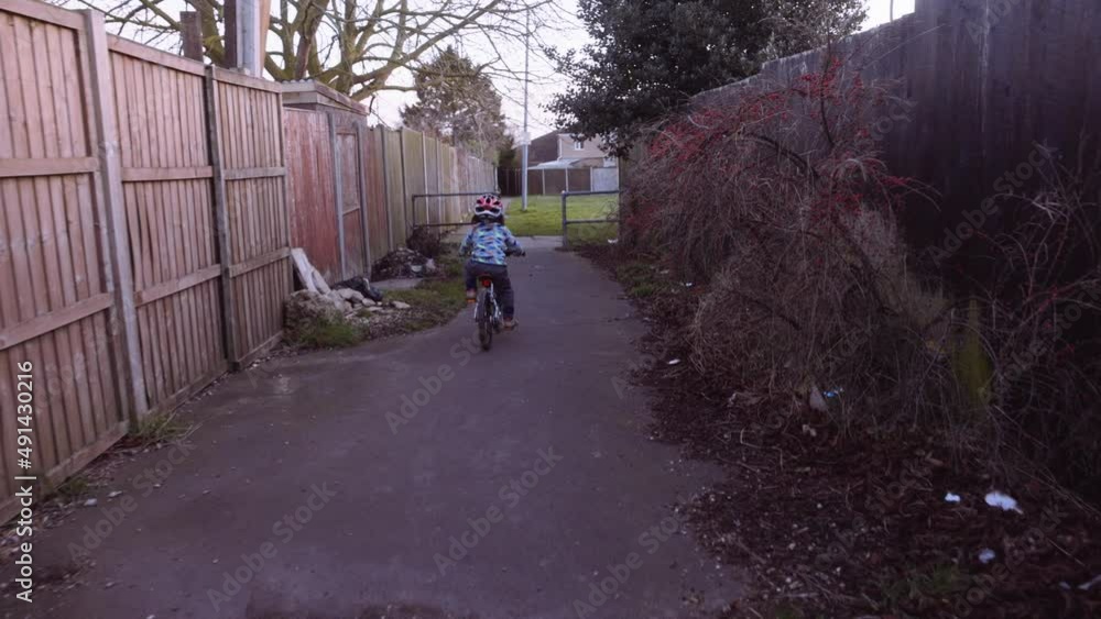 Handheld slow motion shot of an Asian boy riding a bike along a local path. Handheld slow motion shot of an Asian boy riding a bike along a local path.