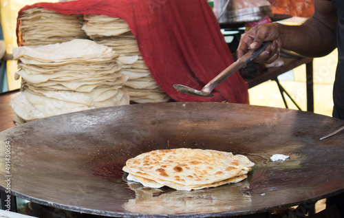 A shop-keeper making egg-roll in the street.