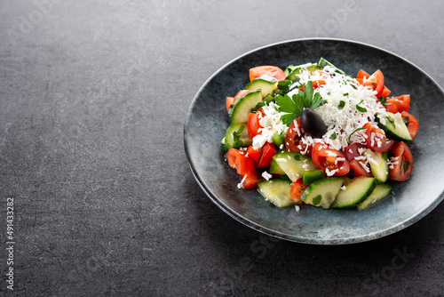 Traditional Bulgarian shopska salad with tomato,cucumber and bulgarian sirene cheese on black background . Copy space