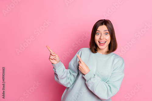 Photo of youth cheerful lady indicate fingers empty space proposition suggest direct isolated over pink color background photo