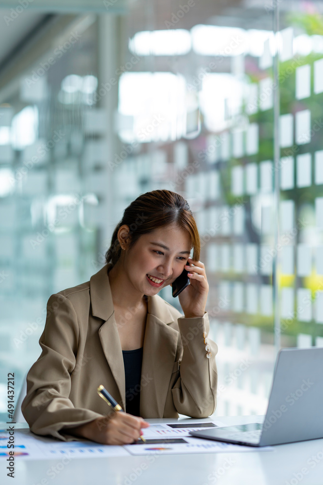 Portrait of a business woman using a laptop and talking on the phone with a customer. Happy working in the office Portrait of a business woman using a laptop and talking on the phone with a customer. Happy working in the office
