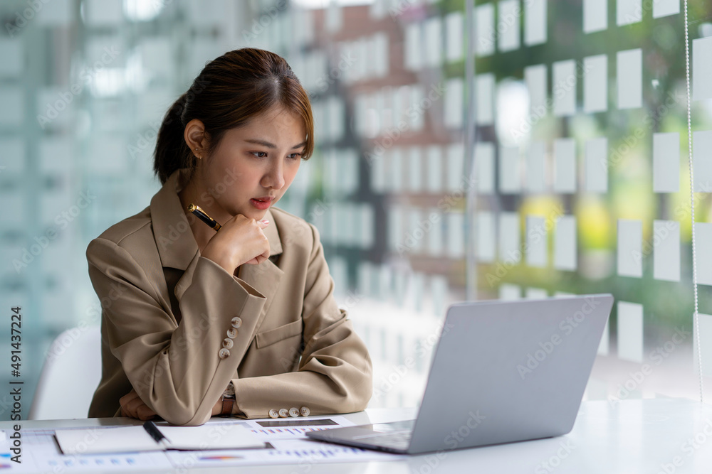 Fototapeta premium Portrait of a business woman who is serious about her work. Using a laptop to check earnings reports report to her boss