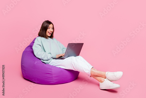 Full length profile side photo of young excited girl speak laptop conference isolated over pink color background
