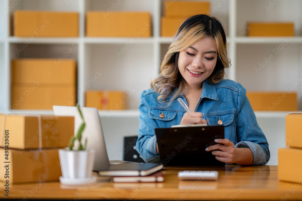 Starting Small business entrepreneur SME freelance,Portrait young woman working at home office, BOX,smartphone,laptop, online, marketing, packaging, delivery, SME, e-commerce concept. Starting Small business entrepreneur SME freelance,Portrait young woman working at home office, BOX,smartphone,laptop, online, marketing, packaging, delivery, SME, e-commerce concept.