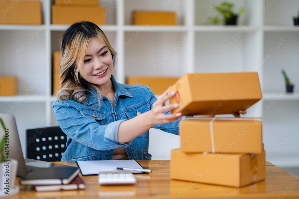Starting Small business entrepreneur SME freelance,Portrait young woman working at home office, BOX,smartphone,laptop, online, marketing, packaging, delivery, SME, e-commerce concept. Starting Small business entrepreneur SME freelance,Portrait young woman working at home office, BOX,smartphone,laptop, online, marketing, packaging, delivery, SME, e-commerce concept.