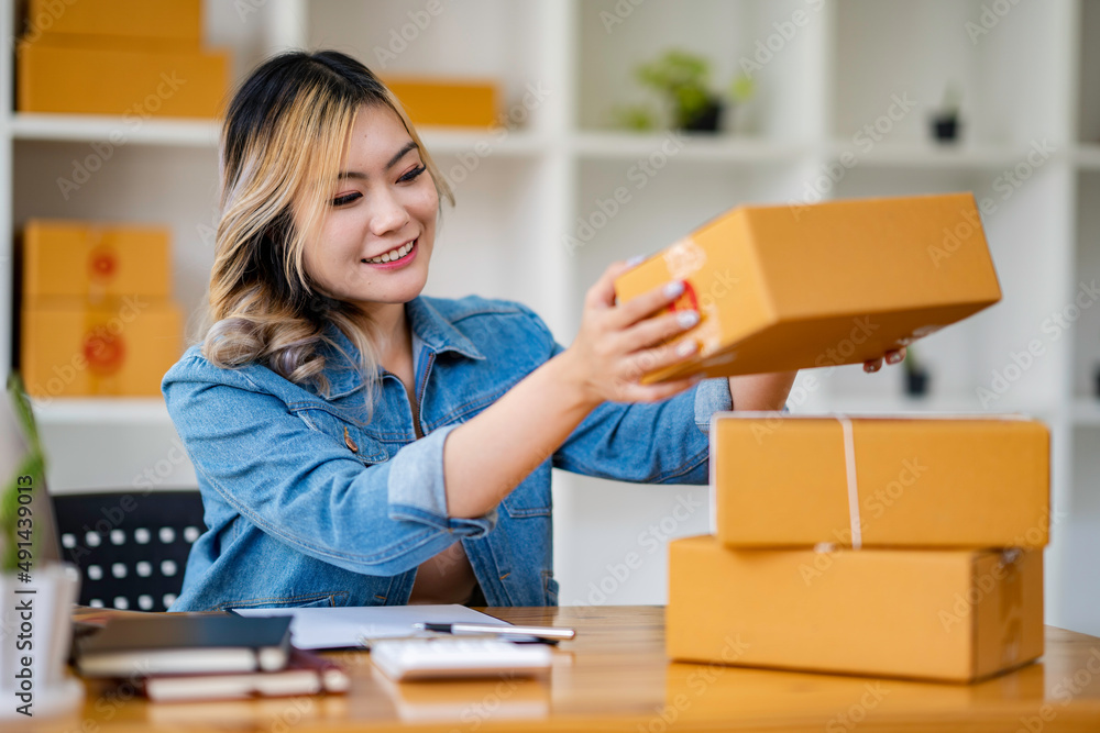 Starting Small business entrepreneur SME freelance,Portrait young woman working at home office, BOX,smartphone,laptop, online, marketing, packaging, delivery, SME, e-commerce concept. Starting Small business entrepreneur SME freelance,Portrait young woman working at home office, BOX,smartphone,laptop, online, marketing, packaging, delivery, SME, e-commerce concept.