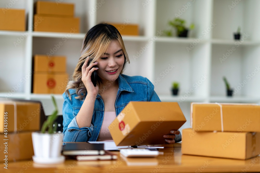 Starting Small business entrepreneur SME freelance,Portrait young woman working at home office, BOX,smartphone,laptop, online, marketing, packaging, delivery, SME, e-commerce concept Starting Small business entrepreneur SME freelance,Portrait young woman working at home office, BOX,smartphone,laptop, online, marketing, packaging, delivery, SME, e-commerce concept