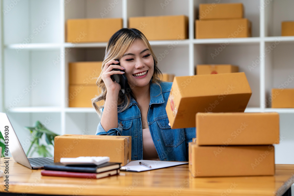Start up small business entrepreneur SME or freelance asian woman using laptop with box, Young success Asian woman with her hand lift up , online marketing packaging box and delivery, SME concept. Start up small business entrepreneur SME or freelance asian woman using laptop with box, Young success Asian woman with her hand lift up , online marketing packaging box and delivery, SME concept.