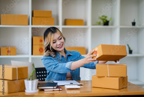 Starting Small business entrepreneur SME freelance,Portrait young woman working at home office, BOX,smartphone,laptop, online, marketing, packaging, delivery, SME, e-commerce concept. © crizzystudio