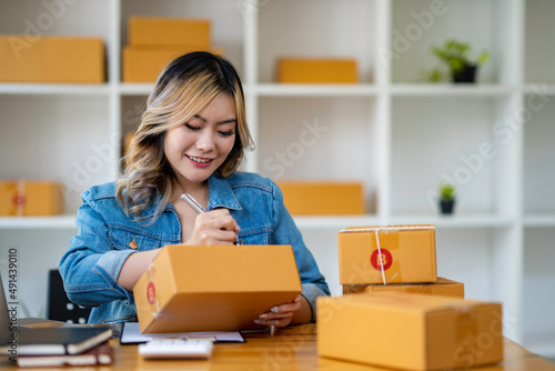 Starting Small business entrepreneur SME freelance,Portrait young woman working at home office, BOX,smartphone,laptop, online, marketing, packaging, delivery, SME, e-commerce concept.