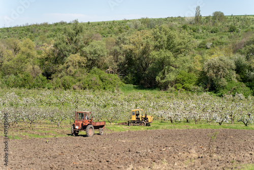 Old Tractor in the Field. Farmer in Old-fashioned tractor sowing crops at field. Woman driving small tractor in field and waving hand