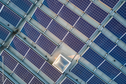 Aerial view of blue photovoltaic solar panels mounted on industrial building roof for producing green ecological electricity. Production of sustainable energy concept