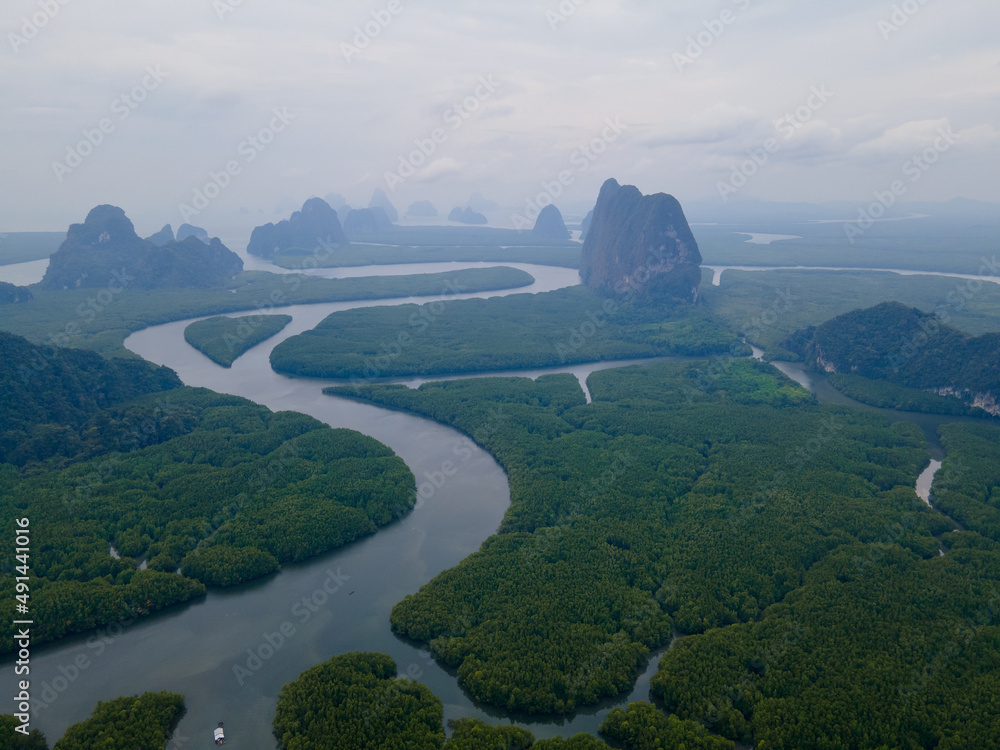 Top and aerial view in area of NAI HGOP pier of Ao Phang - Nga in Thailand show line of water with mangroves along the sides and cloudy sky in evening look like raining.