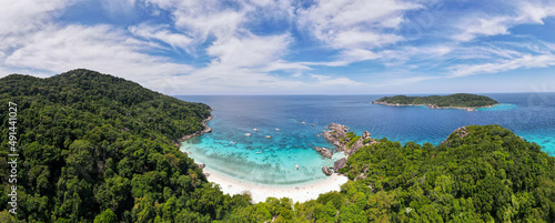 Panorama and aerial view of beach of one island in Similan Islands of Thailand during daylight with sunny sky and some cloud blue sky and emerald water.
