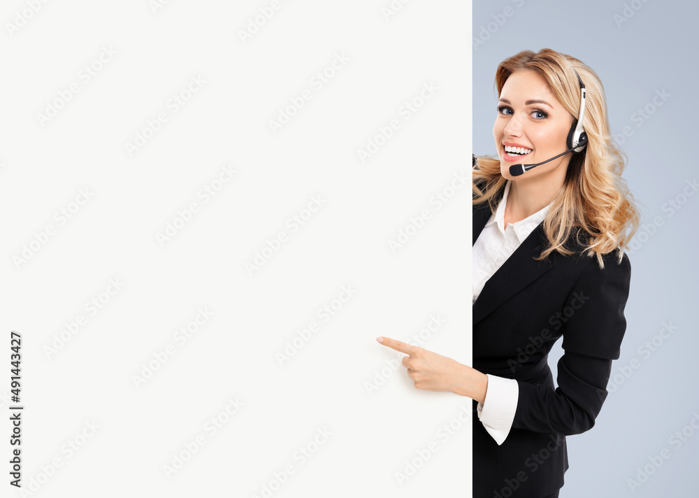 Call center. Customer support service female phone operator or sales agent in headset, confident suit standing behind signboard with copy space area for text, isolated over yellow background