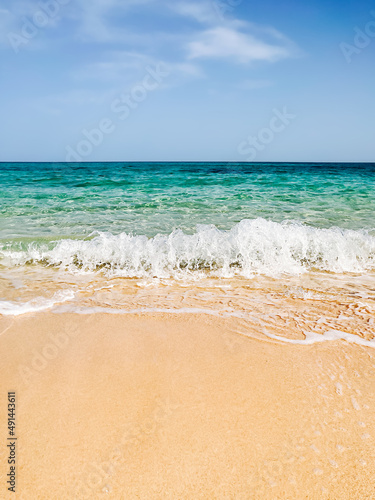 Sea shore sand beach landscape with blue sky background on sun summer day. Ocean vacation concept. Digital detox  isolation on tropical island. White sailboat on wave. Calm  tranquil state of mind.