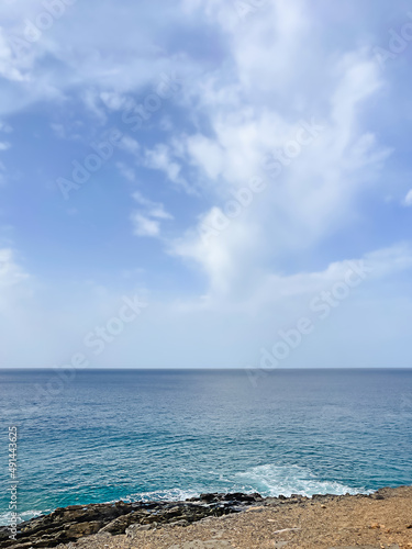 Sea shore sand beach landscape with blue sky background on sun summer day. Ocean vacation concept. Digital detox  isolation on tropical island. White sailboat on wave. Calm  tranquil state of mind.