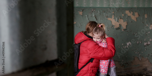 Mother and her daughter in destroyed buildng. War, refugees, war crisis concept. photo