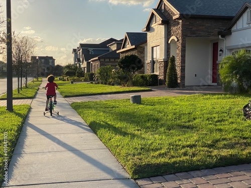 little boy riding bike in his neighborhood on the sidewalk in lake nona florida in orlando 