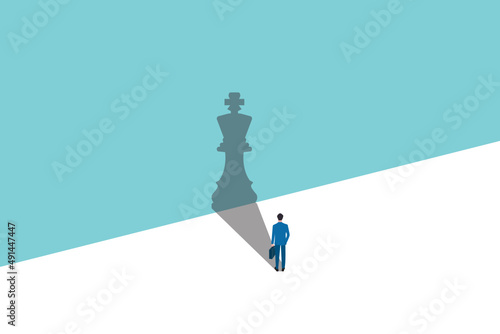 businessman standing with the shadow of a chess king. spotlight that make a shadow of king. trust yourself, self confident concept