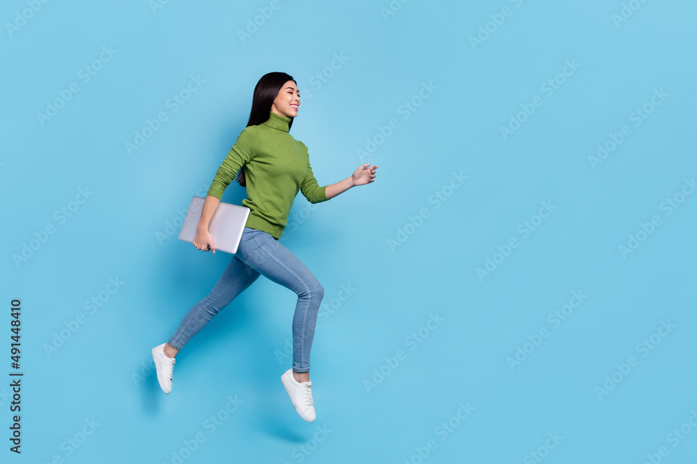Full body photo of funky millennial brunette lady run with laptop wear jumper jeans shoes isolated on blue background Full body photo of funky millennial brunette lady run with laptop wear jumper jeans shoes isolated on blue background