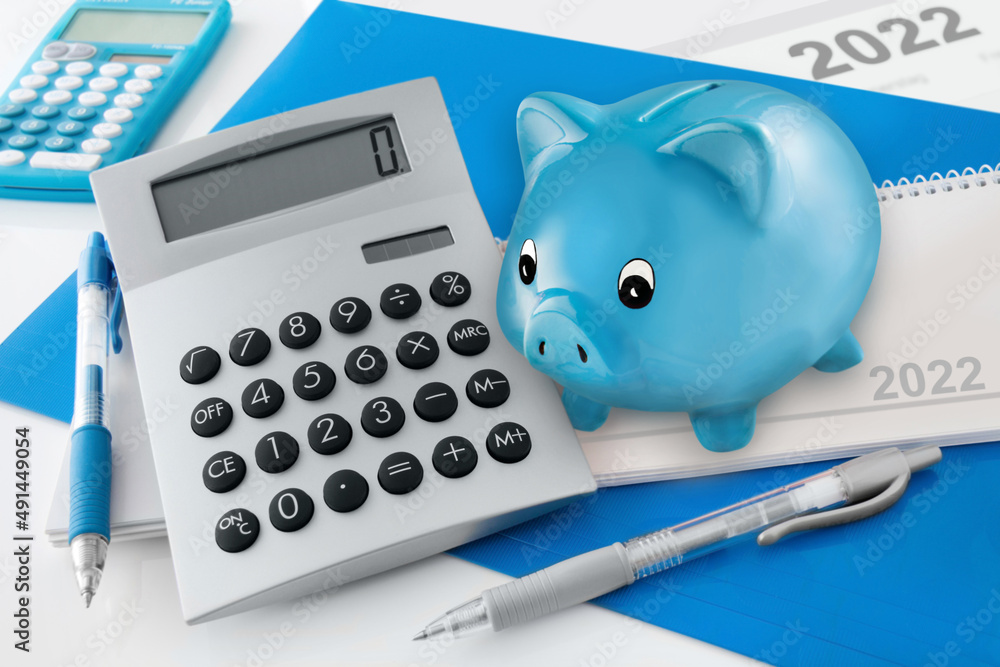 Finanzen und Sparen 2022 mit Sparschwein, Kalender und Rechner auf weissem Hintergrund Finanzen und Sparen 2022 mit Sparschwein, Kalender und Rechner auf weissem Hintergrund