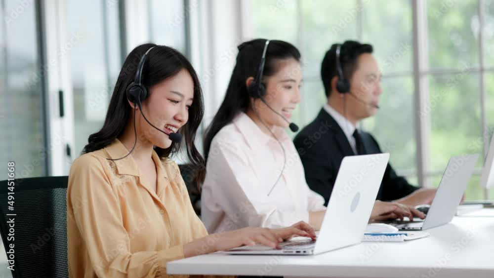 Asian call center team wearing headset and laptop keypad consulting customer in workplace. Group Service Operator Investment advise Business Finance. Active Service mind to customer. White collar Asian call center team wearing headset and laptop keypad consulting customer in workplace. Group Service Operator Investment advise Business Finance. Active Service mind to customer. White collar