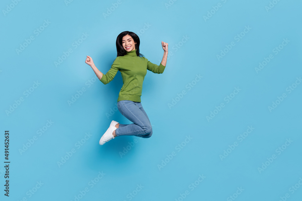 Full body photo of hooray young brunette lady jump yell wear jumper jeans sneakers isolated on blue background Full body photo of hooray young brunette lady jump yell wear jumper jeans sneakers isolated on blue background