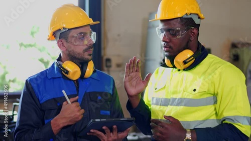 Team multiracial colleague, professional industrial engineer and technician, worker wearing safety uniform, glasses, hard hat, using tablet discuss, analysis, process control in manufacturing factory.