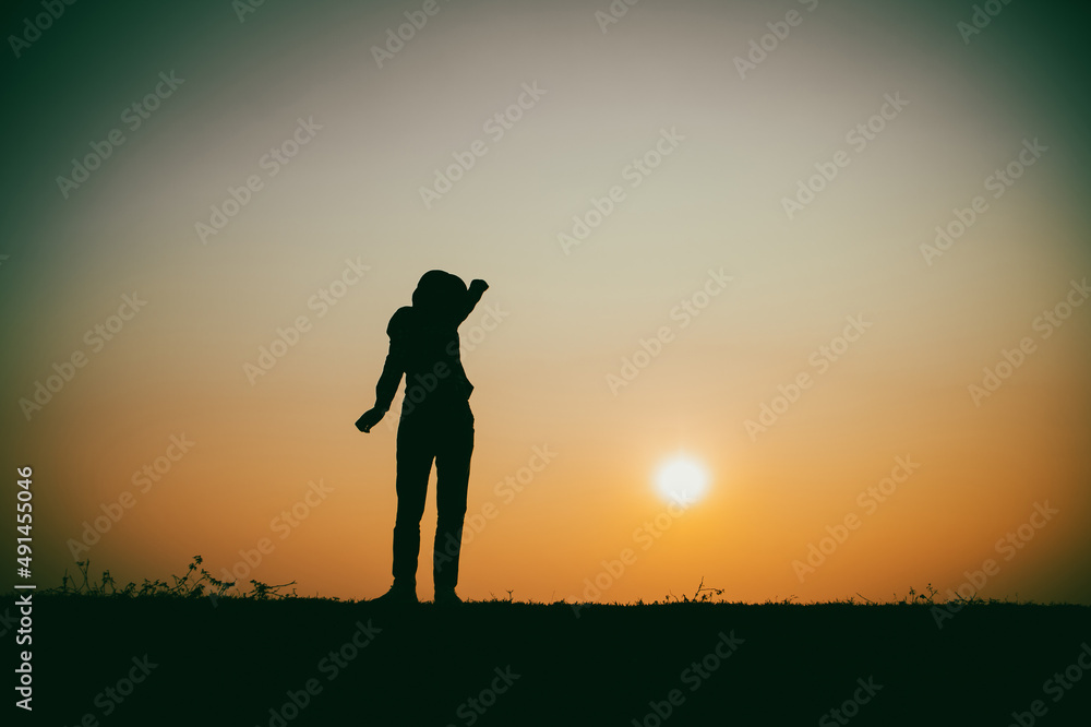 Silhouette of the woman standing lonely at the river during beautiful sunset