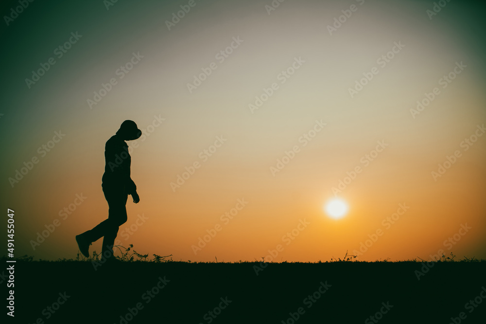 Silhouette of the woman sad walking by the river during sunset Silhouette of the woman sad walking by the river during sunset