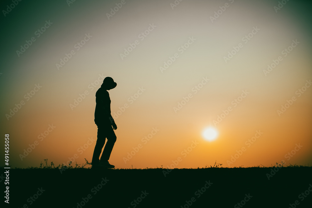 Silhouette of the woman sad walking by the river during sunset